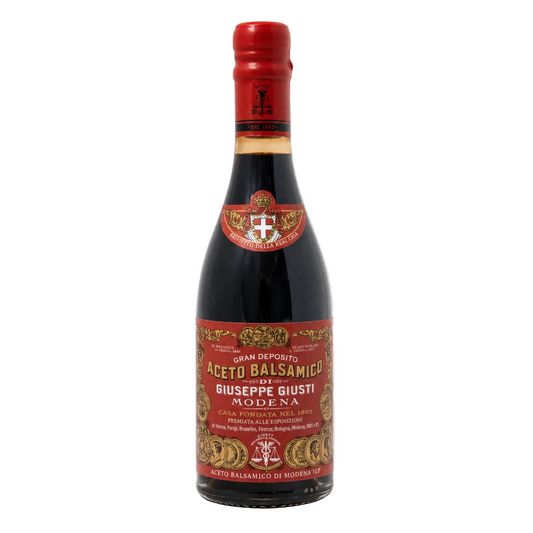 Bottle of Aceto Balsamico with a red label on a white background